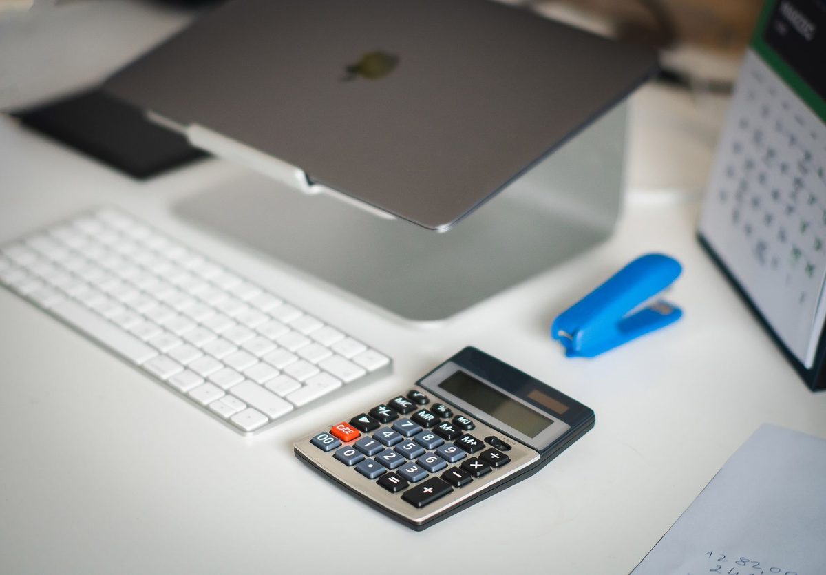 Dueño de una pyme calculando un presupuesto con calculadora y portátil en su escritorio