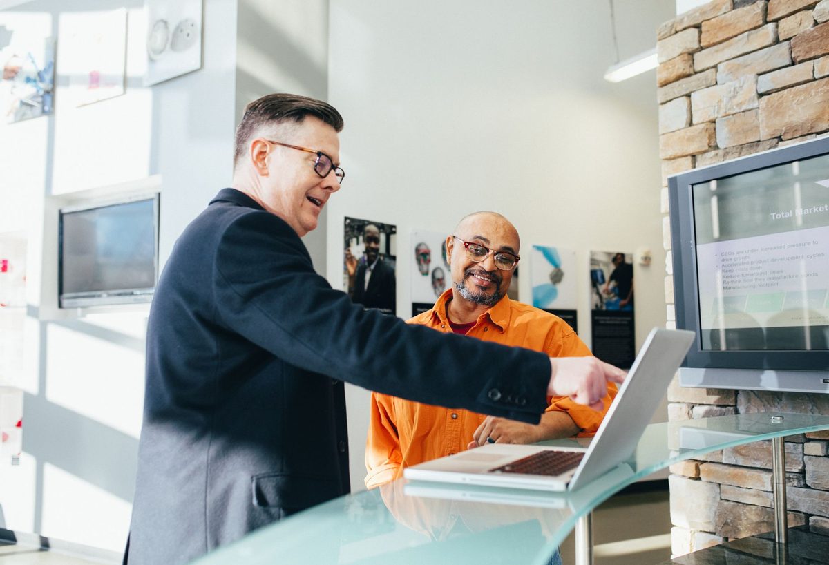 Equipos de marketing y ventas de una empresa trabajando juntos frente a un ordenador en la oficina