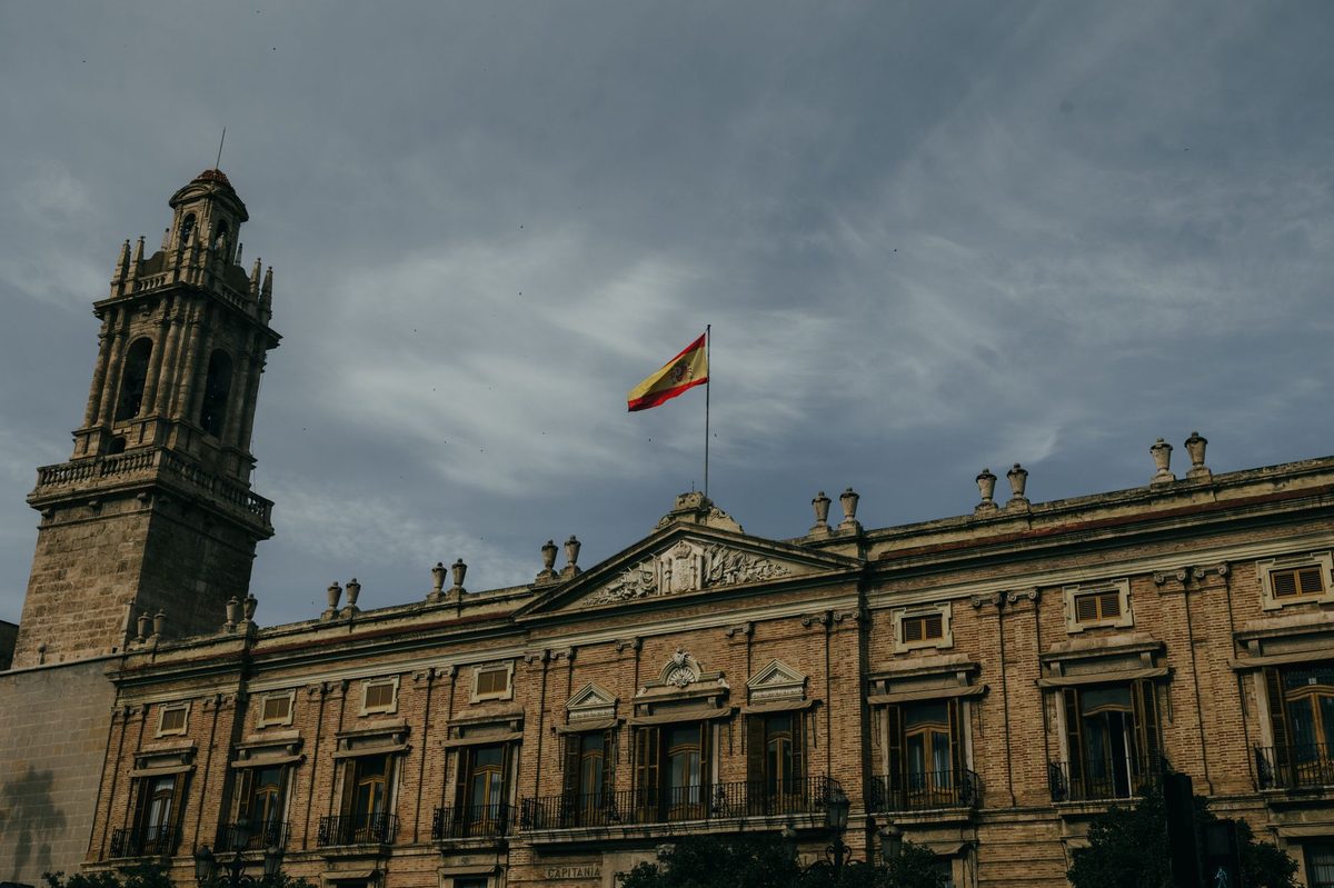 Fachada de un edificio oficial con la bandera de España en lo alto