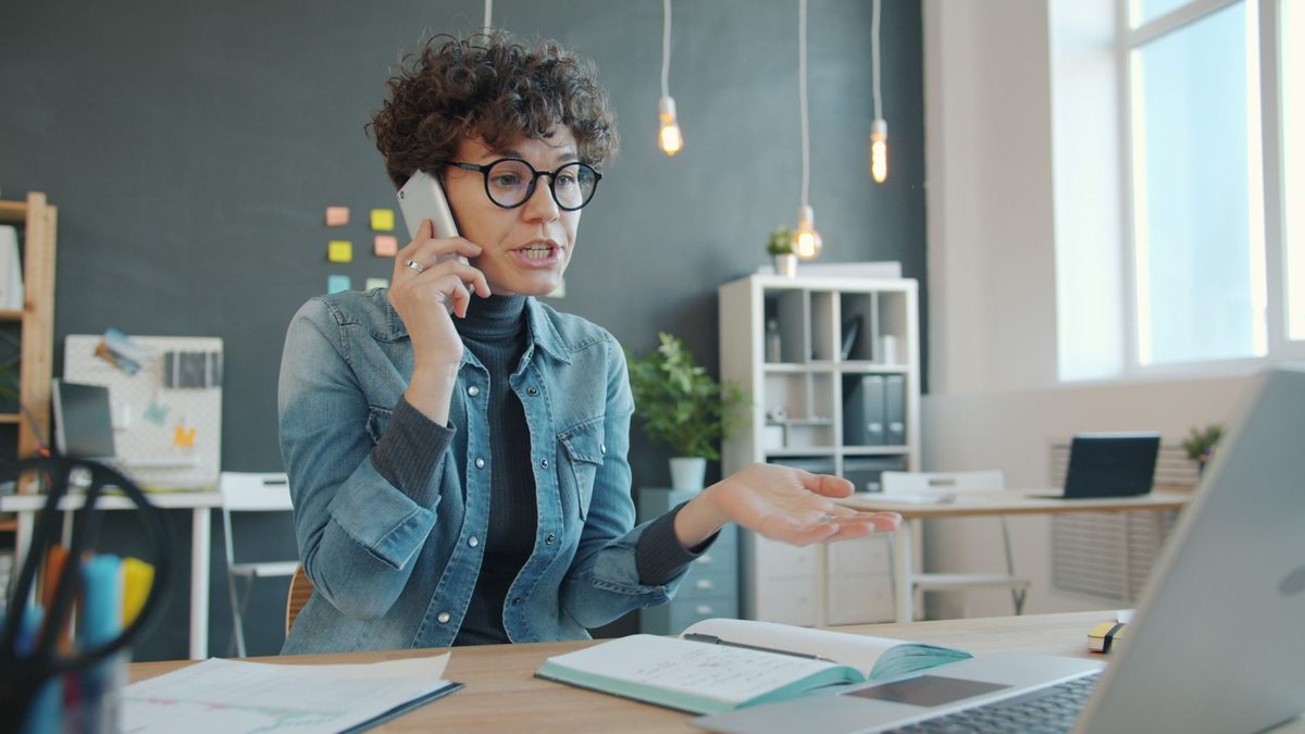 Vendedora atendiendo una llamada comercial desde su mesa de trabajo