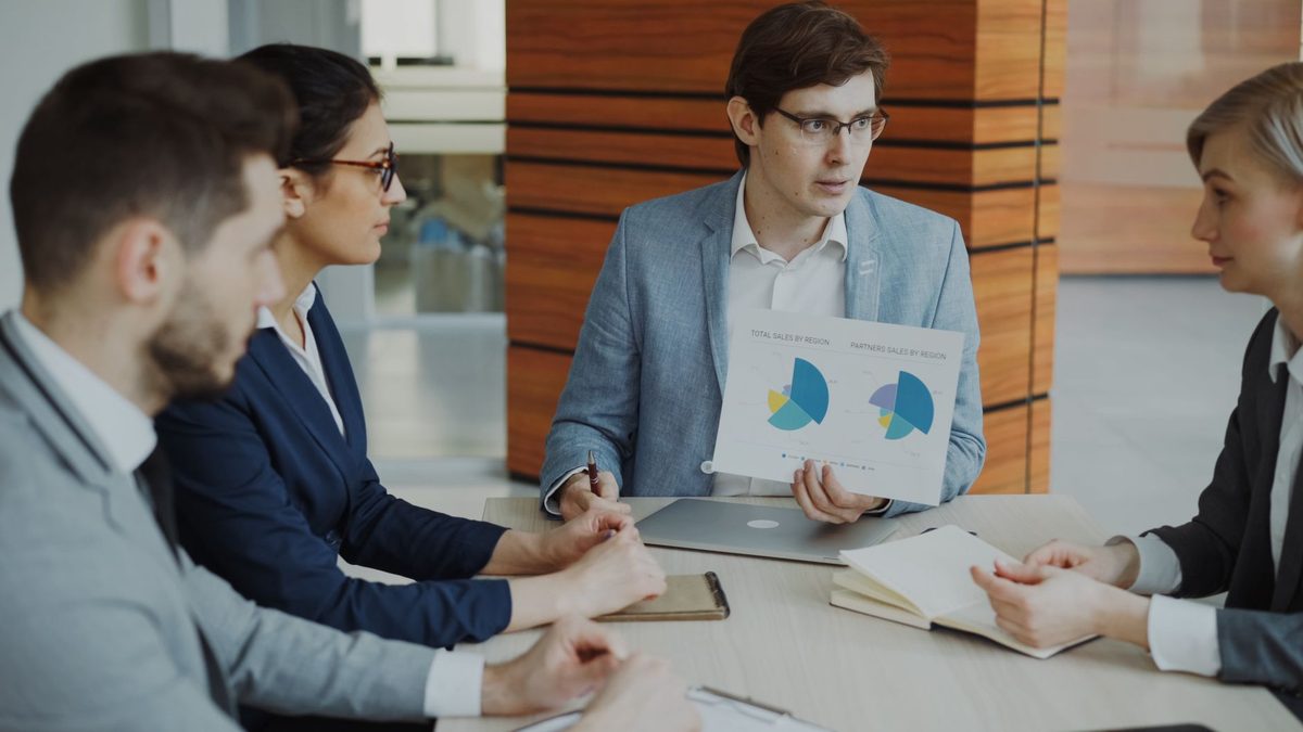 Equipo comercial de una empresa de servicios reunido con portátiles en la oficina