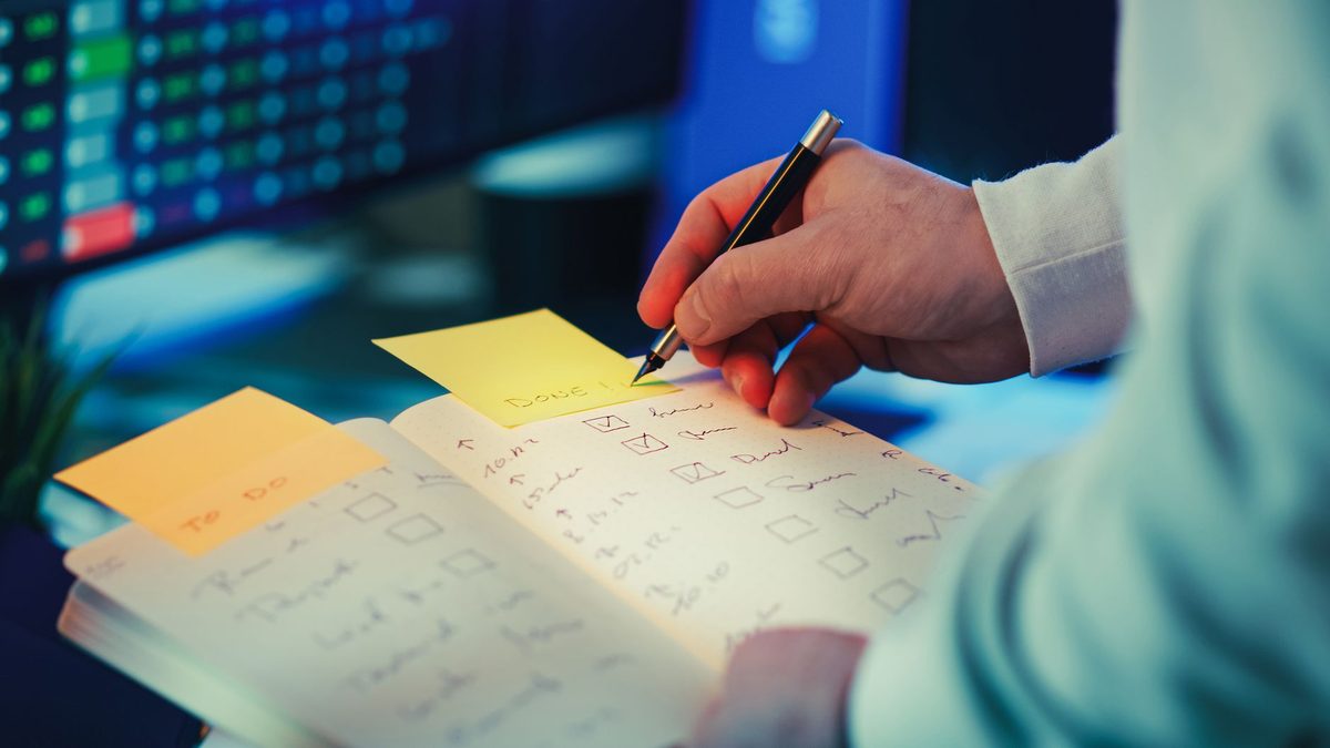 Persona anotando los pasos de un proceso en un cuaderno sobre el escritorio