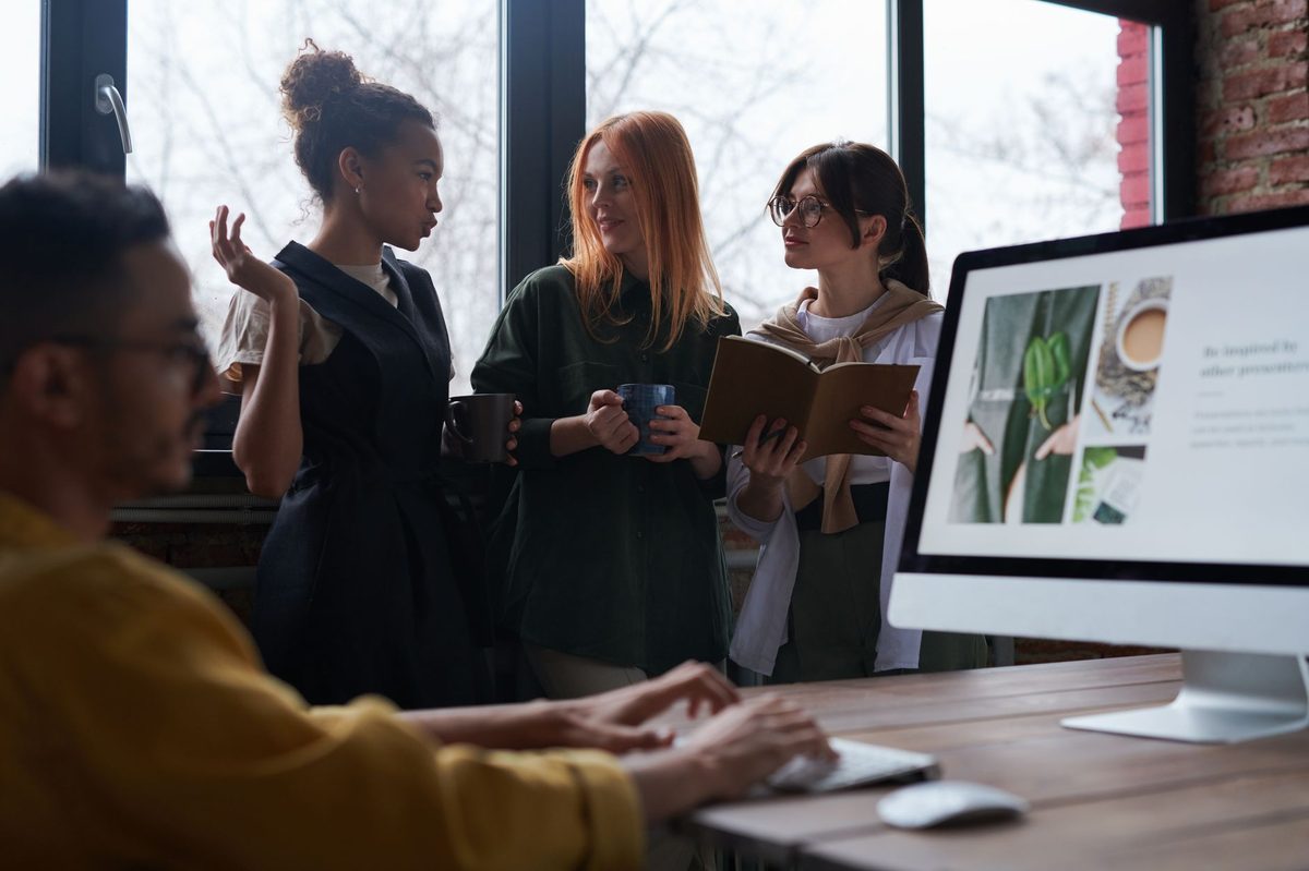 Equipo pequeño de una empresa debatiendo junto a un escritorio en una oficina pequeña